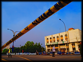 Tali halangan polis berlatarbelakangkan petugas-petugas hari perbarisan